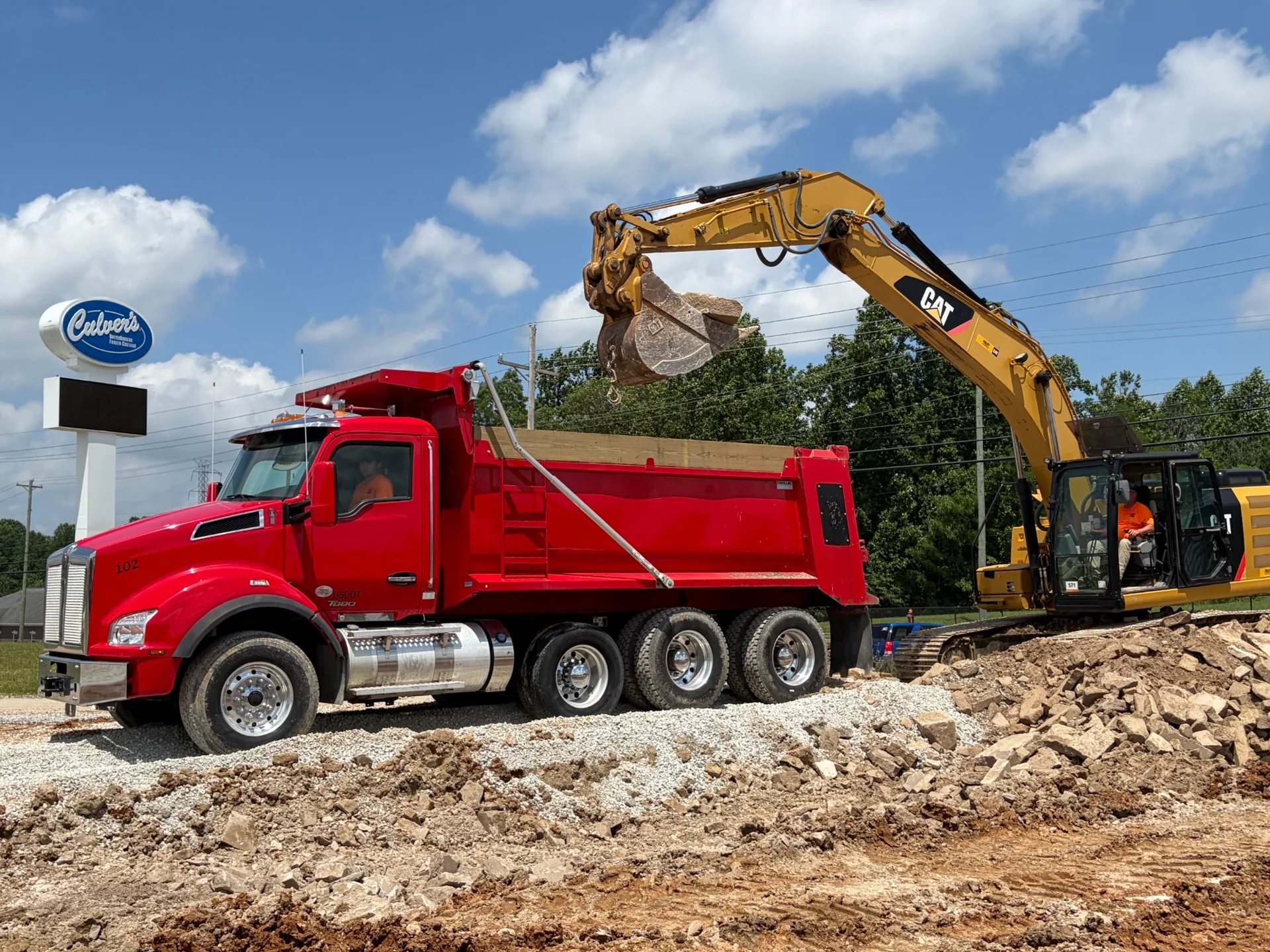 JL Wesley dump truck driver and excavator operator working together on a construction site